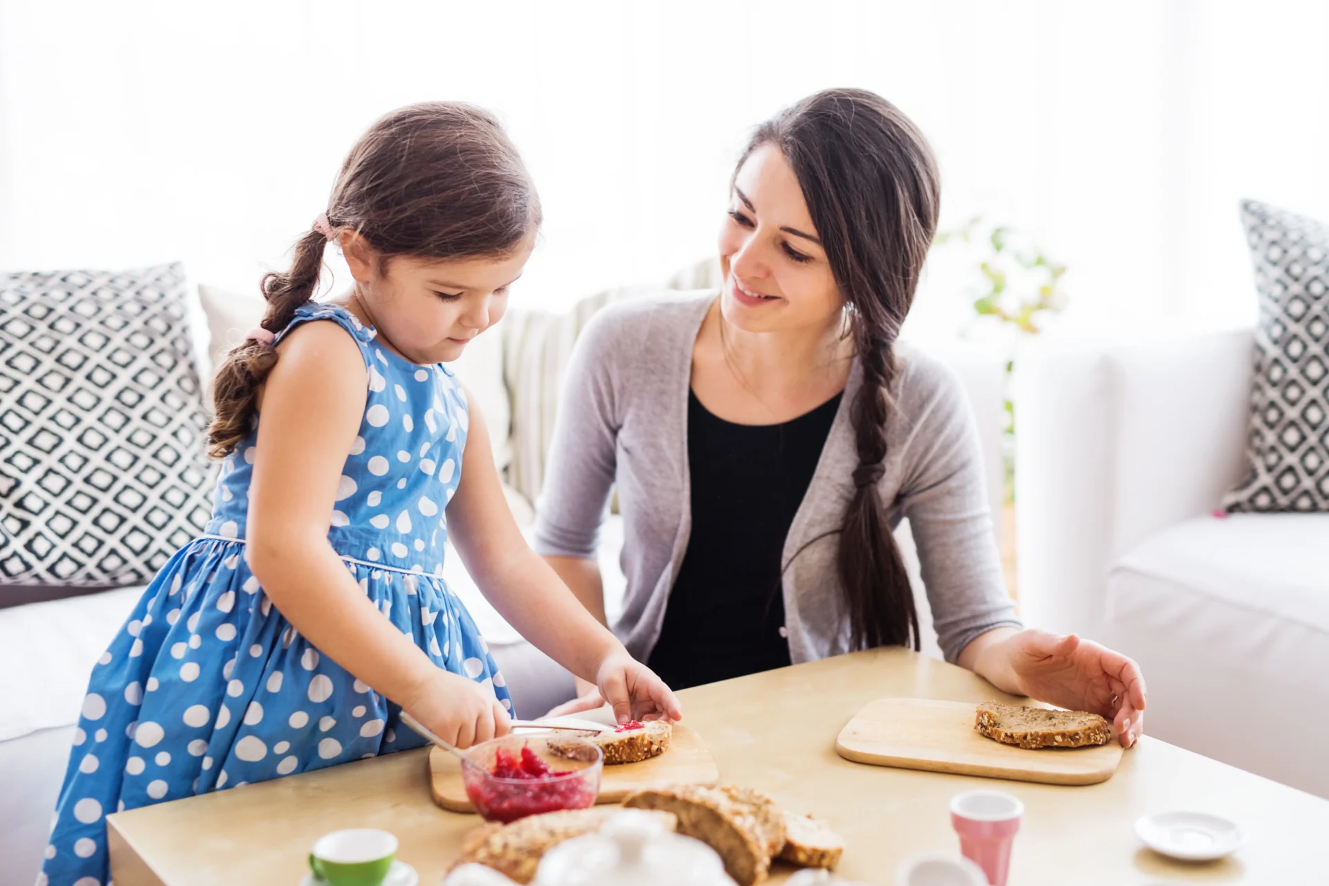 A woman and girl sitting at the table with food.