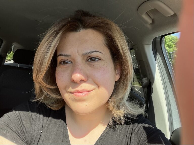 A woman with short hair sitting in the back of a car.