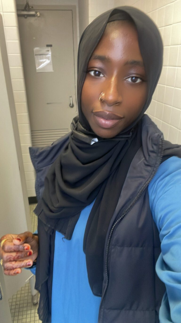 A woman in a black hijab and blue shirt.