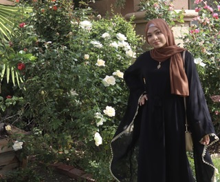 A woman in black dress standing next to flowers.