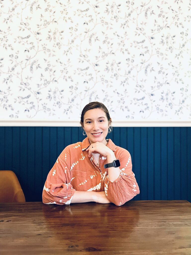 A woman sitting at the table with her hands crossed.