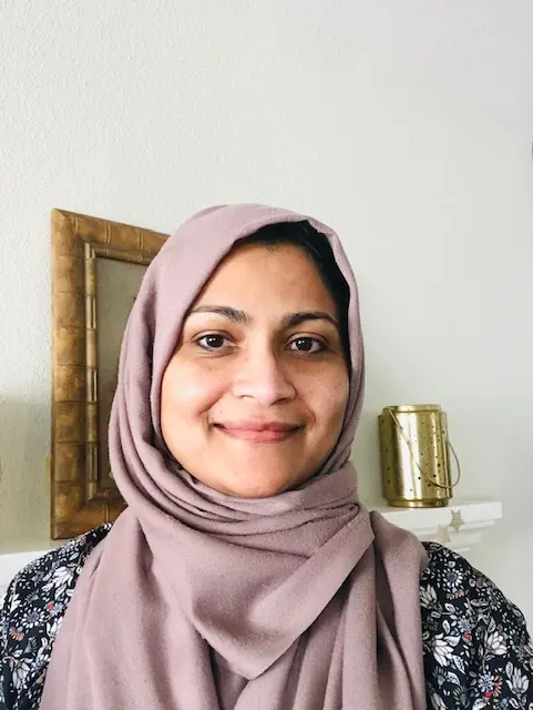 A woman wearing a hijab standing in front of a mirror.