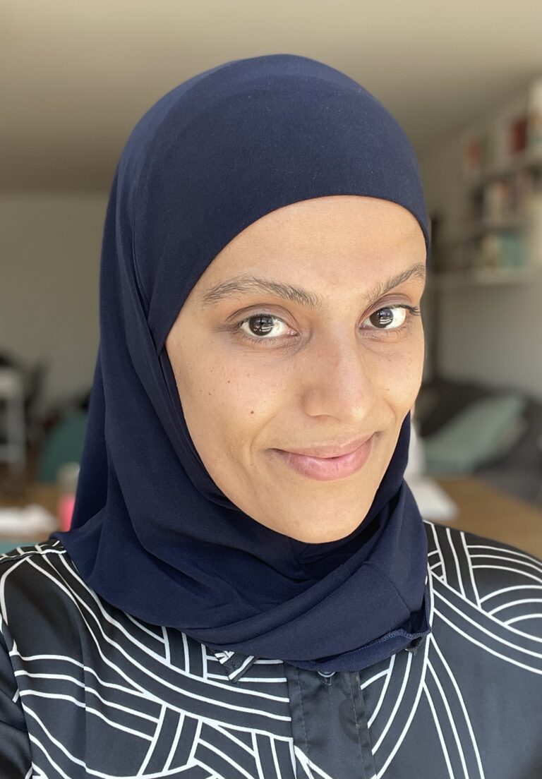 A woman wearing a hijab and smiling for the camera.