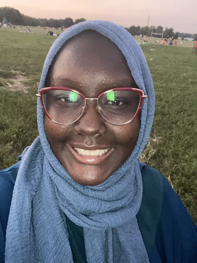 A woman with glasses and a blue head scarf.