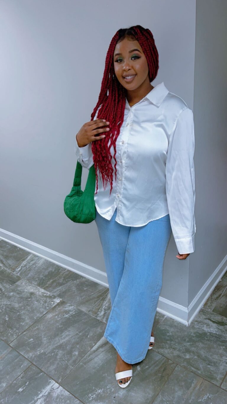 A woman standing in front of a wall wearing white shirt.