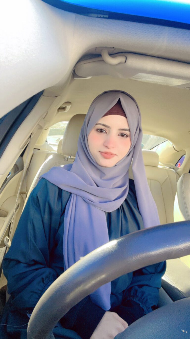 Person sitting in car, wearing a hijab.