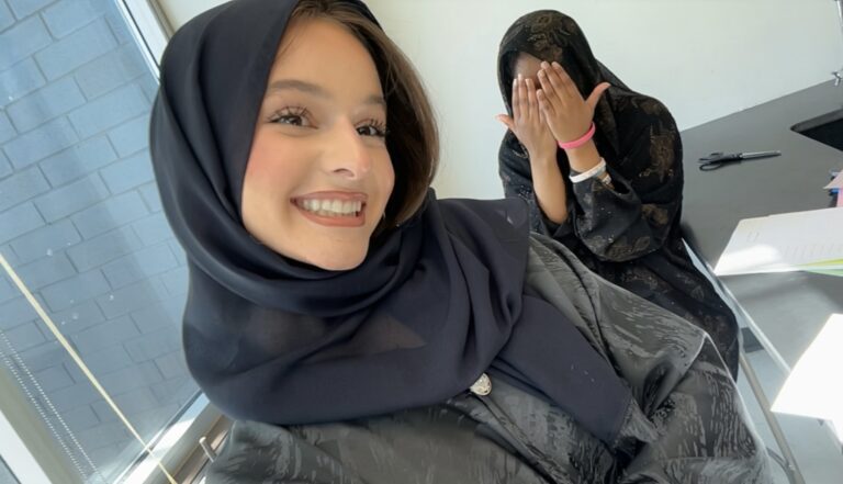 Two women in hijabs, one smiling, indoors.