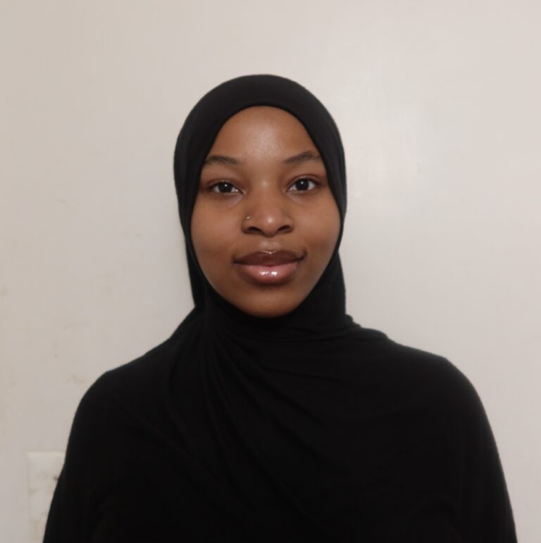 Woman wearing black hijab, neutral background.