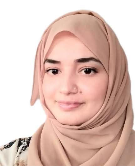 Woman wearing a beige hijab, smiling softly.