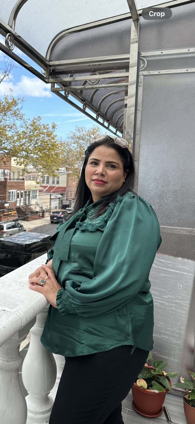Woman in green blouse on balcony outside.