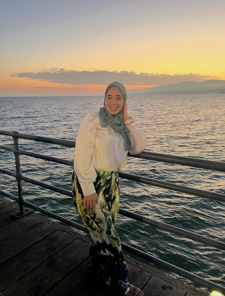Woman on pier at sunset, ocean background.