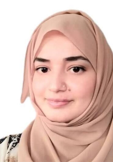 Woman wearing a beige hijab, smiling softly.