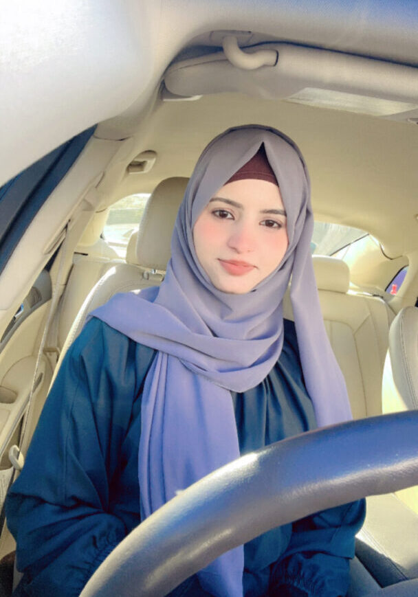 Person sitting in car, wearing a hijab.