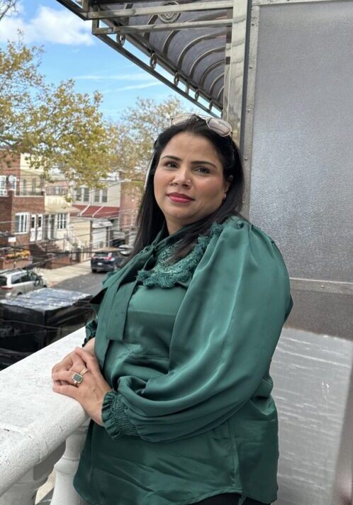 Woman in green blouse on balcony outside.