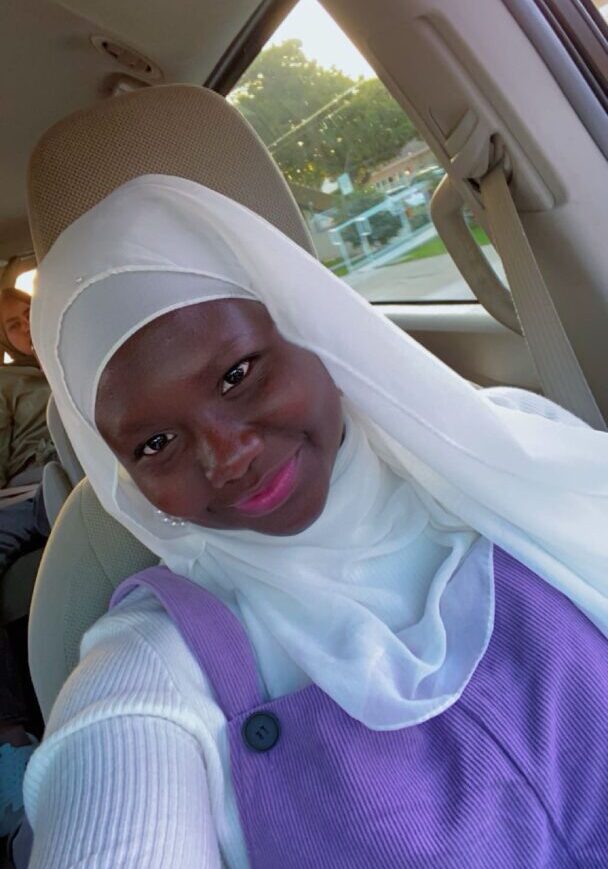 Woman in hijab smiling inside a car.